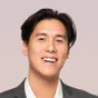 Duy, smiling, in a grey blazer and white shirt