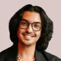 Tim, smiling, with glasses and shoulder-length dark hair